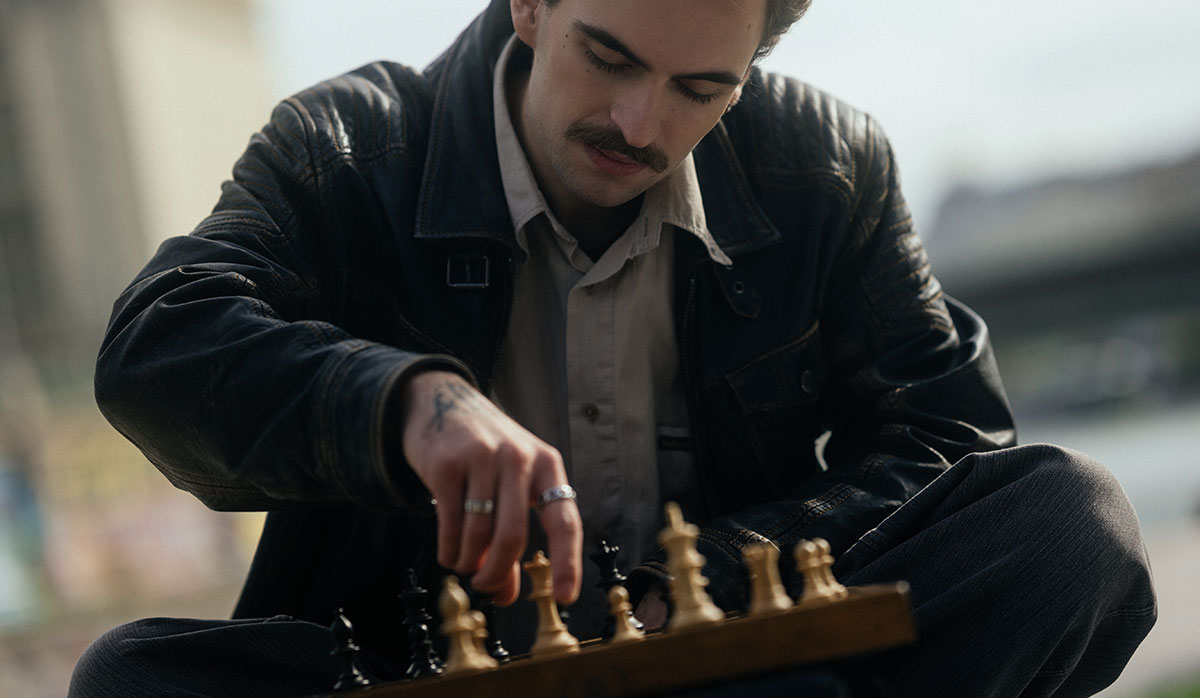 Junger Mann mit Schachbrett Regeln für das erfolgreiche Investieren