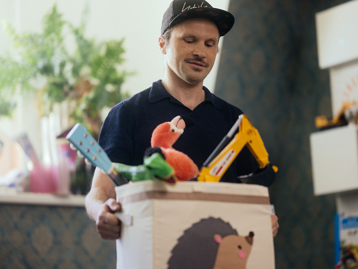 Junger Mann mit Baseballkappe und Spielzeugkiste Vermögensaufbau